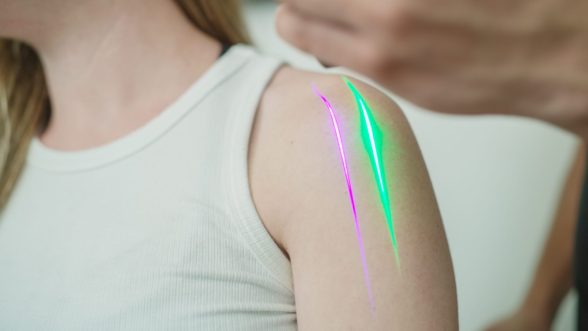 Person receiving colorful light therapy on their upper arm.